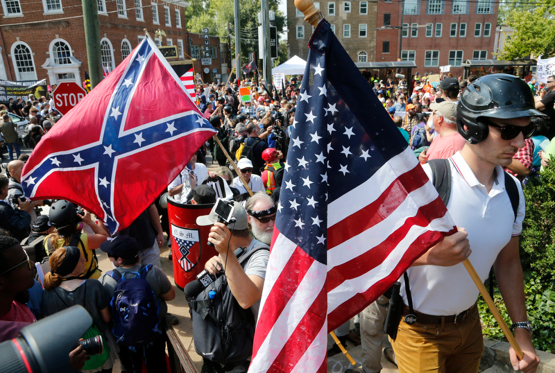 White nationalist demonstrators walk into Lee park surrounded by counter demonstrators in Charlottesville, Va., Saturday, Aug. 12, 2017. Gov. Terry McAuliffe declared a state of emergency and police dressed in riot gear ordered people to disperse after chaotic violent clashes between white nationalists and counter protestors. (AP Photo/Steve Helber)