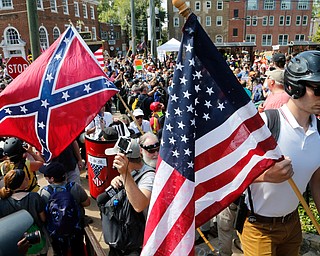 White nationalist demonstrators walk into Lee park surrounded by counter demonstrators in Charlottesville, Va., Saturday, Aug. 12, 2017. Gov. Terry McAuliffe declared a state of emergency and police dressed in riot gear ordered people to disperse after chaotic violent clashes between white nationalists and counter protestors. (AP Photo/Steve Helber)