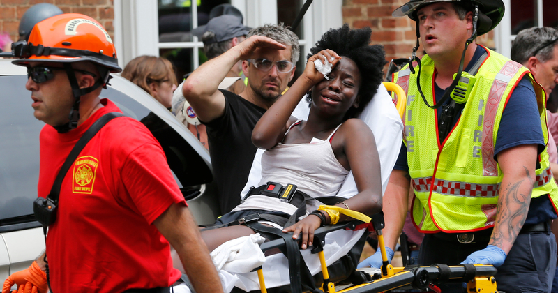 Rescue personnel help an injured woman after a car ran into a large group of protesters after an white nationalist rally in Charlottesville, Va., Saturday, Aug. 12, 2017.  The nationalists were holding the rally to protest plans by the city of Charlottesville to remove a statue of Confederate Gen. Robert E. Lee. There were several hundred protesters marching in a long line when the car drove into a group of them.(AP Photo/Steve Helber)