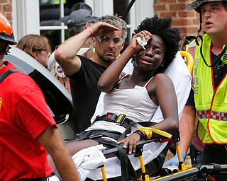 Rescue personnel help an injured woman after a car ran into a large group of protesters after an white nationalist rally in Charlottesville, Va., Saturday, Aug. 12, 2017.  The nationalists were holding the rally to protest plans by the city of Charlottesville to remove a statue of Confederate Gen. Robert E. Lee. There were several hundred protesters marching in a long line when the car drove into a group of them.(AP Photo/Steve Helber)
