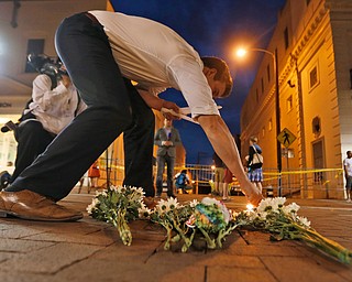Charlottesville resident Elliot Harding lights a candle as he places flowers and a stuffed animal at a makeshift memorial for the victims after a car plowed into a crowd of people peacefully protesting a white nationalist rally earlier in the day in Charlottesville, Va., Saturday, Aug. 12, 2017. (AP Photo/Steve Helber)