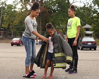 Amauri Taylor(13)(left) helps adjust a firefighter's jacket on her younger sister, Vicki Sly(5)(center) as Niliyah Taylor(15) looks back at a Fire Engine during Rayen Neighborhood Homecoming, Saturday, August 19, 2017 at Rayen Stadium on  in Youngstown's North Side. ..(Nikos Frazier | The Vindicator)