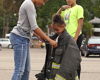 Amauri Taylor(13)(left) helps adjust a firefighter's jacket on her younger sister, Vicki Sly(5)(center) as Niliyah Taylor(15) looks back at a Fire Engine during Rayen Neighborhood Homecoming, Saturday, August 19, 2017 at Rayen Stadium on  in Youngstown's North Side. ..(Nikos Frazier | The Vindicator)