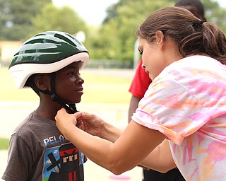 Heather Bielik of YNDC adjusts the helmet straps on Kamron Coleman(8)(north side) during the Rayen Neighborhood Homecoming, Saturday, August 19, 2017 at Rayen Stadium on  in Youngstown's North Side. ..(Nikos Frazier | The Vindicator)