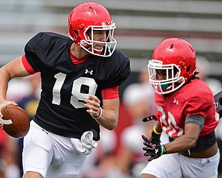 YOUNGSTOWN, OHIO - AUGUST 19, 2017: Youngstown State's Joe Craycraft, black, rolls out away from pressure from Terray Bryant, red, during the teams practice Saturday morning at Stambaugh Stadium. DAVID DERMER | THE VINDICATOR