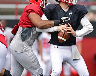 YOUNGSTOWN, OHIO - AUGUST 19, 2017: Youngstown State's Hunter Wells, black, is sacked by Justus Reed, red, during the teams practice Saturday morning at Stambaugh Stadium. DAVID DERMER | THE VINDICATOR