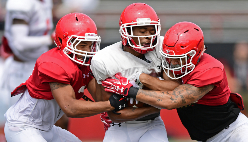 YOUNGSTOWN, OHIO - AUGUST 19, 2017: Youngstown State's Isiah Scott, white, is hit by Billy Nicoe Hurst, right, and Bryce Gibson, left, during the teams practice Saturday morning at Stambaugh Stadium. DAVID DERMER | THE VINDICATOR