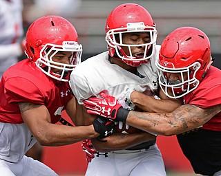 YOUNGSTOWN, OHIO - AUGUST 19, 2017: Youngstown State's Isiah Scott, white, is hit by Billy Nicoe Hurst, right, and Bryce Gibson, left, during the teams practice Saturday morning at Stambaugh Stadium. DAVID DERMER | THE VINDICATOR