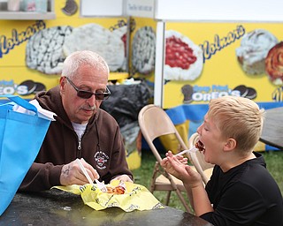 Robert Melewski of Boardman shares a Molnar's cinnamon roll with his grandson, Jordan(10) at the 171st Canfield Fair, Friday, Sept. 1, 2017, at the Canfield Fairgrounds in Canfield...(Nikos Frazier | The Vindicator)