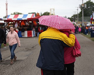 A couple seeks shelter under an umbrella at the 171st Canfield Fair, Saturday, Sept. 2, 2017, at the Canfield Fairgrounds in Canfield...(Nikos Frazier | The Vindicator)