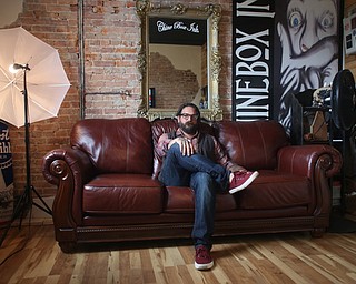 Aaron Chine poses for a photo on the couch in his studio, Thursday, August 24, 2017 at The Box Gallery in Warren...(Nikos Frazier | The Vindicator)