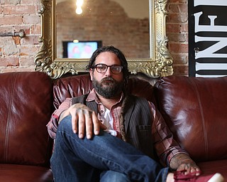 Aaron Chine poses for a photo on the couch in his studio, Thursday, August 24, 2017 at The Box Gallery in Warren...(Nikos Frazier | The Vindicator)