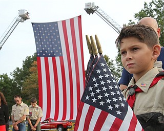 William D. Lewis the vindicator  Aiden Cordona, 12, a member of Boy Scout Troop 22 in Austintown, holds American flags during a 911 ceremony at Austintown 911 park Monday 9-11-17. Behind him is a large American Flag draaped from Fire ladders.