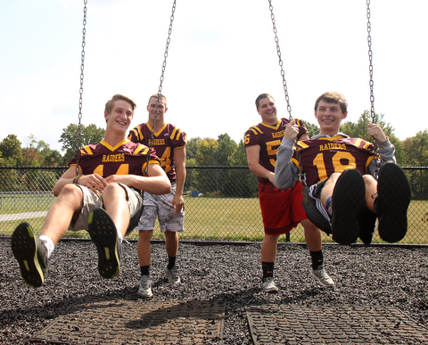 South Range running back Peyton Remish (44)(center left) and South Range offensive lineman Matt Brooks (56)(center right) push South Range running back Peyton Remish (44)(left) and South Range wide receiver Mathias Combs (18)(right) on a swing set while posing for a portrait, Tuesday, Sept. 19, 2017, on a school playground at South Range High School in Canfield. ..(Nikos Frazier | The Vindicator)