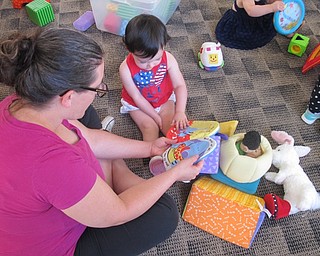 Neighbors | Zack Shively .A mother read a book to her baby at Bonding with Babies at the Austintown library on Aug. 15.