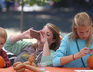 Nora Novak(center) of Boardman, takes a photo of her son, Beckham(3) as he and his sister, Harley(15) paint pumpkins during the Boardman Rotary's annual Oktoberfest, Oct. 1, 2017, at Boardman Park in Boardman...(Nikos Frazier | The Vindicator)