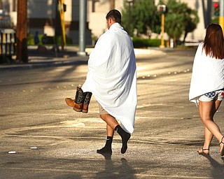 People walk near the Las Vegas Strip shortly after sunrise Monday, Oct. 2, 2017, in Las Vegas. A deadly shooting occurred Sunday at a music festival on the Las Vegas Strip. (AP Photo/Ronda Churchill)