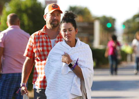 Melissah Burke and her husband Stephen, of Seattle, walk along the Las Vegas Strip near Mandalay Bay hotel and casino Monday, Oct. 2, 2017, in Las Vegas. The couple, who were attending the music festival last night where a mass shooting occurred, found refuge in a nearby apartment and casino. (AP Photo/Ronda Churchill)