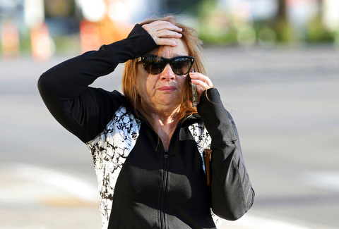 A woman speaks on the phone while walking along the Las Vegas Strip near Mandalay Bay hotel and casino Monday, Oct. 2, 2017, in Las Vegas. A mass shooting occurred late night Sunday at a music festival on the Las Vegas Strip. (AP Photo/Ronda Churchill)