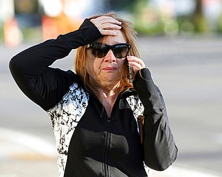 A woman speaks on the phone while walking along the Las Vegas Strip near Mandalay Bay hotel and casino Monday, Oct. 2, 2017, in Las Vegas. A mass shooting occurred late night Sunday at a music festival on the Las Vegas Strip. (AP Photo/Ronda Churchill)