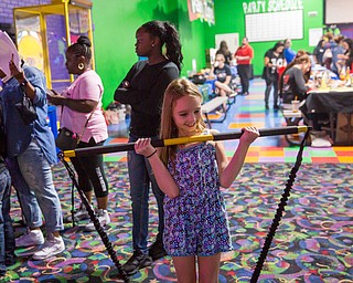 Nine-year-old Adrianna Seale of Austintown tries out a resistant band from the Planet Fitness area during the Community Day event at Skate Zone on Saturday. Local businesses provided free activities for the community.