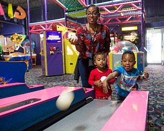 Two-year-old Tristan Washington of Campbell takes a shot at ski-ball with Sarai Broomfield, 2 (center) and her mother Nichelle Scott of Austintown during the first Skate Zone Community Day on Saturday.