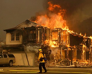 A firefighters walks near a home in Santa Rosa, Calif., Monday, Oct. 9, 2017. Wildfires whipped by powerful winds swept through Northern California sending residents on a headlong flight to safety through smoke and flames as homes burned. (AP Photo/Jeff Chiu)