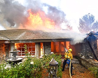 Firefighters work to extinguish a fire at a home as they battle a wildfire in Anaheim Hills, Calif., Monday, Oct. 9, 2017. Wildfires whipped by powerful winds swept through Northern California sending residents on a headlong flight to safety through smoke and flames as homes burned. (Jeff Gritchen/The Orange County Register via AP)