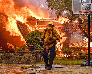 Firefighters work to extinguish a fire at a home as they battle a wildfire in Anaheim Hills, Calif., Monday, Oct. 9, 2017. Wildfires whipped by powerful winds swept through Northern California sending residents on a headlong flight to safety through smoke and flames as homes burned. (Jeff Gritchen/The Orange County Register via AP)