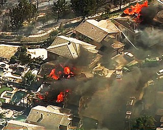 In this image made from a video provided by KABC-TV, a fire burns in the Anaheim Hills area of Anaheim, Calif., in northern Orange County in Southern California on Monday, Oct. 9, 2017. Wildfires whipped by powerful winds swept through Northern California sending residents on a headlong flight to safety through smoke and flames as homes burned. (KABC-TV via AP)