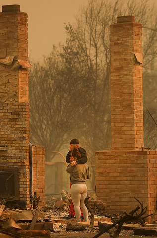 Darin Garcia looks at the remains of his home he's lived in for nearly 40 years as he embraces Ashley Alva, Monday Oct. 9, 2017 in the Coffey Park area of Santa Rosa, Calif. More than a dozen wildfires whipped by powerful winds been burning though California wine country. The flames have destroyed at least 1,500 homes and businesses and sent thousands of people fleeing. (Kent Porter/The Press Democrat via AP)