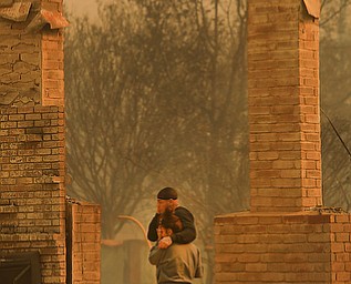 Darin Garcia looks at the remains of his home he's lived in for nearly 40 years as he embraces Ashley Alva, Monday Oct. 9, 2017 in the Coffey Park area of Santa Rosa, Calif. More than a dozen wildfires whipped by powerful winds been burning though California wine country. The flames have destroyed at least 1,500 homes and businesses and sent thousands of people fleeing. (Kent Porter/The Press Democrat via AP)