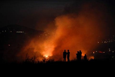 People watch as a wildfire burns along a hillside Monday, Oct. 9, 2017, in Orange, Calif. Authorities say at least half a dozen homes have burned in a fast-moving brush fire in Southern California. (AP Photo/Jae C. Hong)