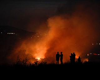 People watch as a wildfire burns along a hillside Monday, Oct. 9, 2017, in Orange, Calif. Authorities say at least half a dozen homes have burned in a fast-moving brush fire in Southern California. (AP Photo/Jae C. Hong)