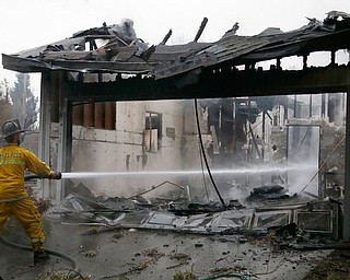 A Santa Rosa firefighter hoses down a hotspot in the Coffey Park area of Santa Rosa, Calif., on Tuesday, Oct. 10, 2017. An onslaught of wildfires across a wide swath of Northern California broke out almost simultaneously then grew exponentially, swallowing up properties from wineries to trailer parks and tearing through both tiny rural towns and urban subdivisions. (AP Photo/Ben Margot)