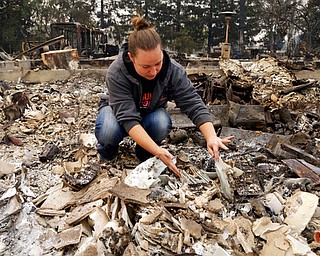 Gina Baier looks for family heirloom china that may have survived in the remains of her home in the Coffey Park area of Santa Rosa, Calif., on Tuesday, Oct. 10, 2017. An onslaught of wildfires across a wide swath of Northern California broke out almost simultaneously then grew exponentially, swallowing up properties from wineries to trailer parks and tearing through both tiny rural towns and urban subdivisions. (AP Photo/Ben Margot)
