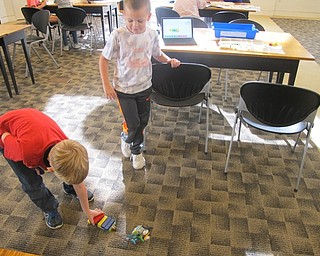 Neighbors | Zack Shively.Children placed blocks on the back of the Lego trailer to see if their Lego robot could continue moving across the floor at the Austintown library's Lego WeDo Robots event.