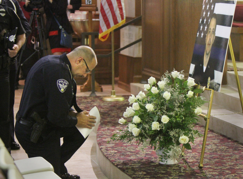 William D Lewis The Vindicator Niles PD officer Chris Manella pauses in front of a photo of slain Girard PD officer Justin Leo during a prayer vigil at St. rose Church in Girard 10-24-17.