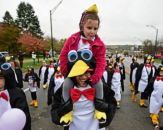 YOUNGSTOWN, OHIO - OCTOBER 28, 2017: Paisley McKee of Cortland rides on the shoulder of David Kovacs from Cortland while they are both dressed as penguins while marching on Fifth Avenue during the YSU homecoming parade, Saturday afternoon. DAVID DERMER | THE VINDICATOR