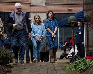 Rebecca Devereaux | The Vindicator ..Bill Douglas carries a rose to place on the Vietnam Memorial in memory of his brother Tom Douglas during the annual laying of the rose ceremony in downtown Youngstown on Sunday. Douglas walks with his grandchildren Afton Douglas, 9 (center), Zoey Douglas, 11 and his wife Sharon Douglas of New Middletown pictured behind.