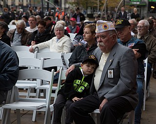 Rebecca Devereaux | The Vindicator ..Four-year-old Corey Riley of Pittsburgh leans on his grandfather Rege Riley, American Veterans First Vice Commander of Pittsburgh, during the annual Laying of the Roses Ceremony in Downtown Youngstown on Sunday.