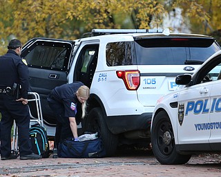 A police officer watches as a paramedic tends to a man after an apparent assault, Monday, Nov. 6, 2017, at the Covington St. and Broadway St. in Youngstown...(Nikos Frazier | The Vindicator)