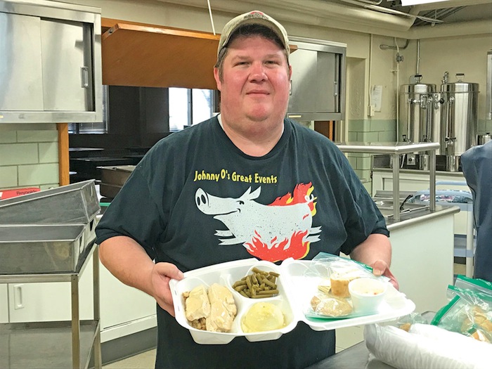 Johnny Opritza, volunteer chef at Bethel Lutheran Church, holds a stuffed chicken dinner during last week’s dinner. The next sale will take place Dec. 14 and will feature a holiday turkey and cranberry sandwich. A portion of the proceeds will benefit local missions in the area. See vindy.com for video about the event.