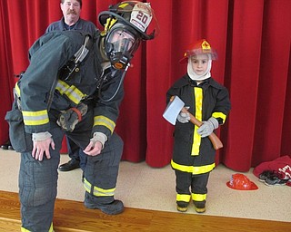 Neighbors | Zack Shively.Firefighter Cameron Long and Bill Williams explained and demonstrated the fire gear firefighters use to stay safe. First-grader Aubrey Macovitz-Verindek also put on fire gear with help from firefighter Sarah Anton during the presentation.