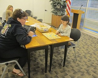 Neighbors | Zack Shively.The Austintown library had a "Playtime at Your Library" event. The child pictured solved a puzzle by searching for number pieces in the sandbox next to her.