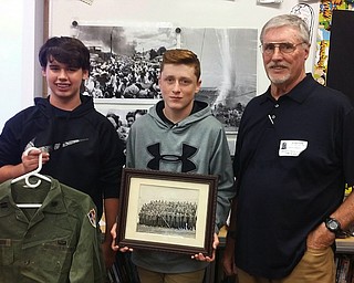 Above, from left, are Justin Benson, holding Gleason’s uniform; Hunter Baum, holding a picture of Gleason’s battalion; and Patrick T. Gleason. Below, Gleason shows the students his uniform and shared some of his experiences during Vietnam.
