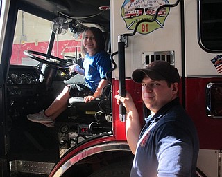 Neighbors | Zack Shively.Poland Union student Allie Nigh (left) sat behind the wheel of one of Poland's fire trucks during the school's visit to the fire station. Volunteer firefighter Jake Ezzo (right) helped her in and out of the truck.