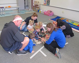 Neighbors | Zack Shively.The children and parents made craft apple pies. They used aluminum foil pie pans, fake crust and cotton balls painted red to look like apples. Some of the children went over to the stove playset to place the pie in oven.