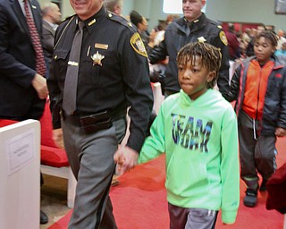 William D. Lewis the Vindicator Trumbull County Sheriff Paul Monroe wals shand in hand with Devin Sanders, 7, during a MLK Celebration Service at Second Baptist Church in Warren 1-14-18. A number of area officers attending the service and were escorted by local children.