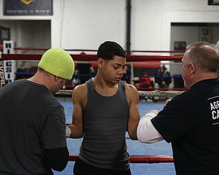 Brayan Colon(center) waits as trainer Vinny O'Neil and coach Jack Loew tie his gloves, Tuesday, Jan. 16, 2018, at the Southside Boxing Gym in Youngstown...(Nikos Frazier | The Vindicator)